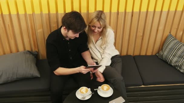 Junges Paar schaut auf Tablet und trinkt Kaffee — Stockvideo