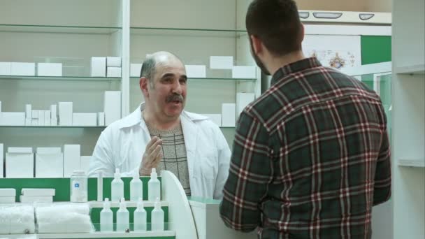 Positieve senior druggist client medicijnen bij de apotheek geven — Stockvideo