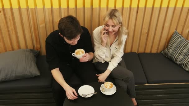 Молодая веселая женщина разговаривает по мобильному телефону, встречаясь в кафе — стоковое видео