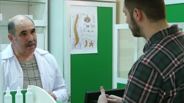 Senior apotheker en jonge klant bespreken van medicijnen — Stockvideo