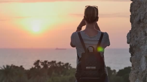 Telefonunda günbatımı deniz fotoğraf çekici sırt çantası ile kadın Gezgin — Stok video