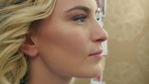 Vista lateral do blush sendo aplicado em maçãs do rosto da bela mulher loira — Vídeo de Stock