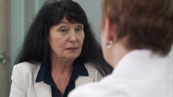 Äldre kvinnlig kund talar med kvinnliga läkare på sjukhus — Stockvideo