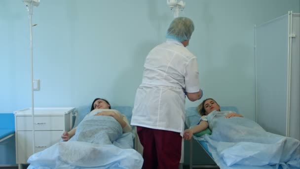 Enfermera poniendo paciente femenino en un goteo en una sala de hospital — Vídeos de Stock