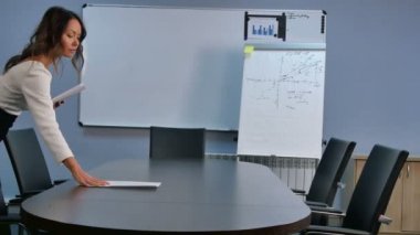 Resepsiyon ofis kağıtları koyarak genç Asyalı Sekreteri salonu toplantı için hazırlanıyor