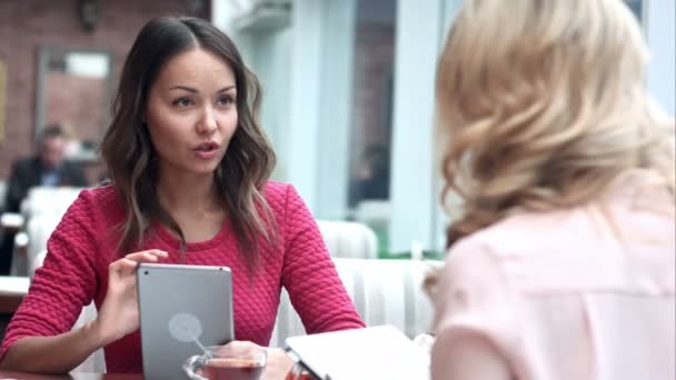 Duas mulheres sentadas no café rústico olhando para fotos em tablet digital — Vídeo de Stock