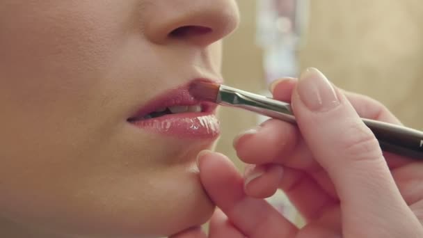 Make-up-Artist verwendet Pinsel, um Lipgloss auf Modellippen aufzutragen — Stockvideo
