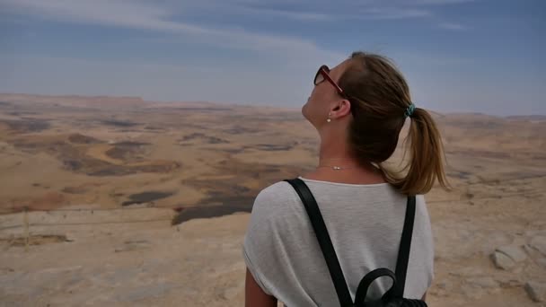 Jonge vrouw met rugzak staande op de rand van de kliffen op zoek naar hemel en draaien — Stockvideo