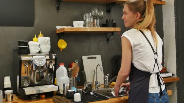 Молода бариста миє посуд на робочому місці — стокове відео