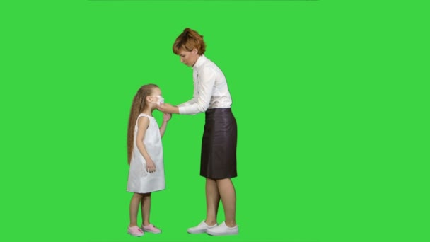 Молода мати надягла медичну маску своїй маленькій дівчинці на зелений екран, Chroma Key — стокове відео