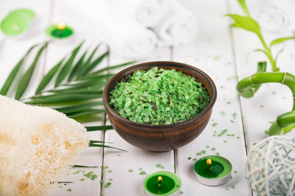 Spa. Sal de espirulina de hierbas verdes en tazón de cerámica, toallas de spa, velas y bambú — Foto de Stock