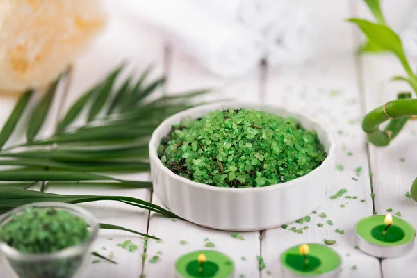 Spa. Sal de espirulina de hierbas verdes en tazón de cerámica blanca, toallas de spa, velas y bambú — Foto de Stock