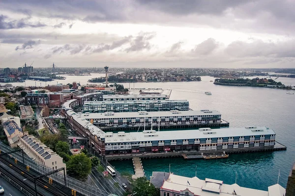 Kirribilli yacht club, de landtong en de jachthaven voor stad Sydney Cbd, harbour bridge en bezienswaardigheden rond de wateren van Sydney Harbour onder bewolkte hemel. — Stockfoto