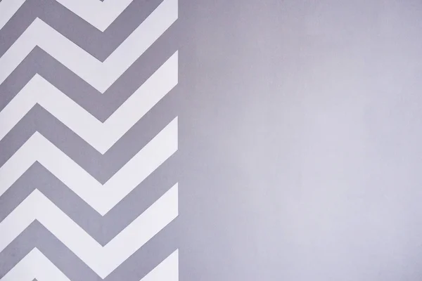 Pintar una pared con cinta adhesiva. tiras de zigzag blanco en la pared gris. La pared terminada — Foto de Stock