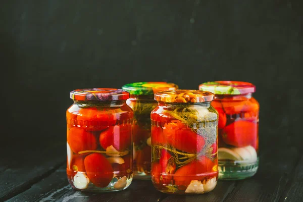 Vários jarros de tomates enlatados com tomates maduros e alho — Fotografia de Stock