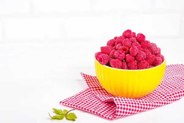 Fresh raspberry in a modern yellow bowl on light background — Stock Photo, Image