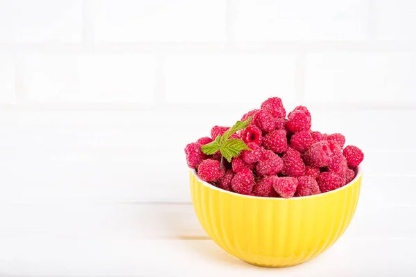 Fresh raspberry in a modern yellow bowl on light background — Stock Photo, Image