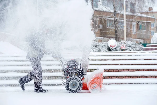 Schneeräumarbeiten mit einer Schneefräse. Mann räumt Schnee. Starke Niederschläge und Schneehaufen. — Stockfoto