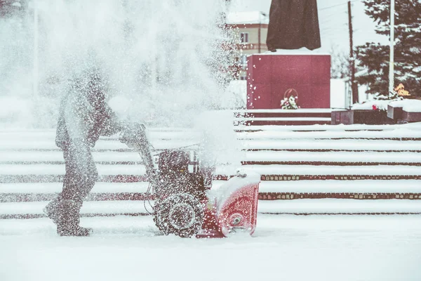 Schneeräumarbeiten mit einer Schneefräse. Mann räumt Schnee. Starke Niederschläge und Schneehaufen. — Stockfoto
