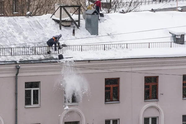 Team männlicher Arbeiter säubert Dach des Gebäudes vom Schnee mit Schaufeln bei der Sicherung von Mantra-Gürteln. — Stockfoto