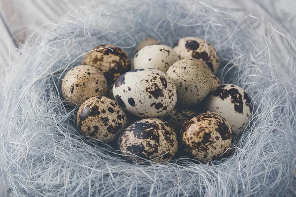 Decoración de Pascua. Huevos de codorniz en un nido sobre un fondo de madera — Foto de Stock