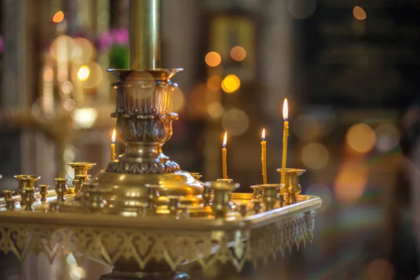 Burning yellow candles in the Church, standing on a pedestal — Stock Photo, Image