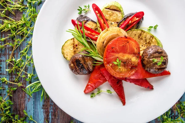Różne pyszne mięso z grilla z warzywami i ziołami na rustykalnym stole — Zdjęcie stockowe