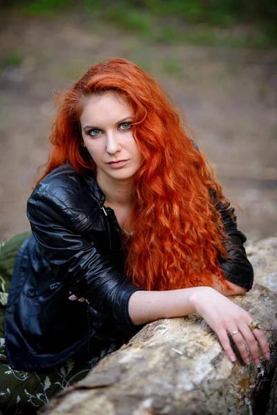 Pretty young sexy fashion sensual red hair woman posing in a forest background dressed in hipster rock style outfit, leather jacket. — Stock Photo, Image