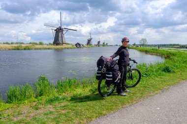 Kinderdijk, Hollanda - Mayıs 2019. O Kinderdijk 'in yel değirmenlerini ziyaret ederken turist bisikleti sürüyor. Kinderdijk 'in yel değirmenleri Hollanda' nın en tanınmış turistik alanlarından biridir..