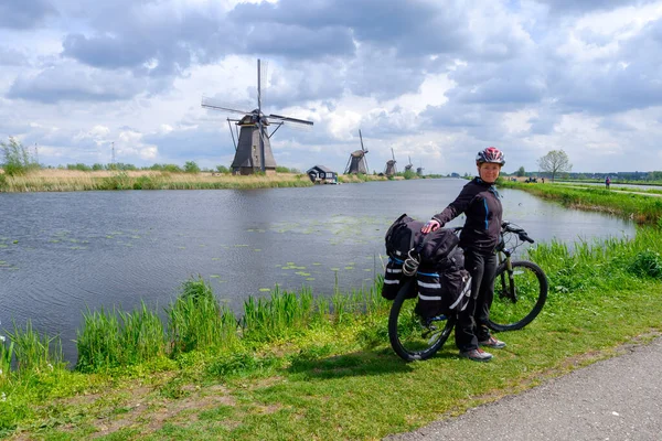 Kinderdijk, Netherlands - May, 2019. Tourist ride bicycle as she visit the windmills of Kinderdijk. The windmills of Kinderdijk are one of the best-known Dutch tourist sites. — 图库照片