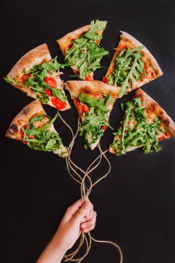 Kadın elinde siyah arka planda pizza balonları tutuyor.