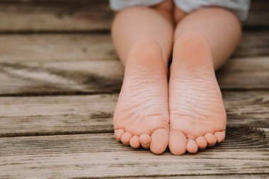 Ahşap bir iskelede oturan çocuk