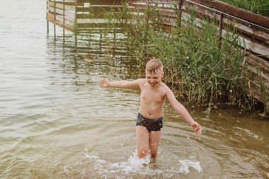 Çocuk göl kıyısında suda oynuyor. Yaz tatilleri. Yumuşak odak