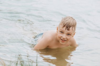 Çocuk göl kıyısında suda oynuyor. Yaz tatilleri. Yumuşak odak