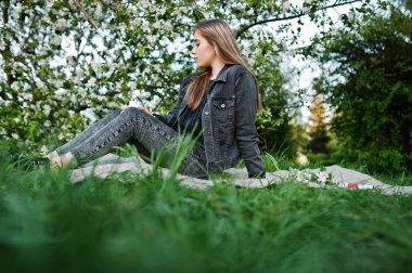 Kot ekose Bahar çiçeği ağacına oturan genç esmer kız.