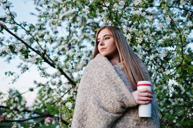 Bahar çiçeği ağaç ve holding çay termosu elinde karşı ekose genç esmer kız.