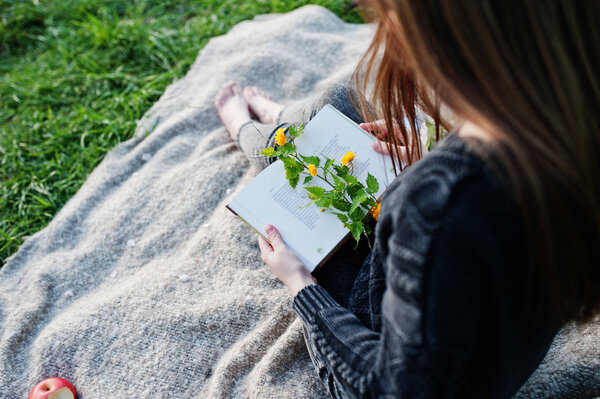 Молодая брюнетка сидит на клетке и читает книгу
.