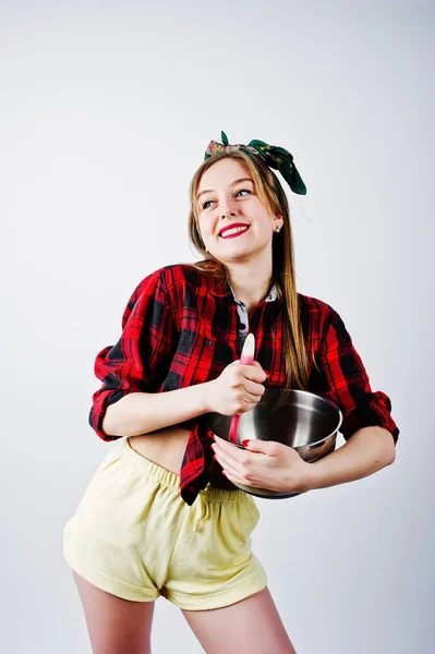 格子縞のシャツと黄色ショーツ ピンのアップ スタイル鍋 キッチン スプーンで白い背景で隔離の若い面白い主婦 — ストック写真