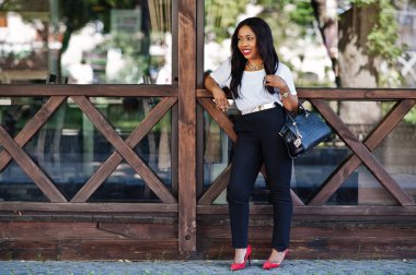 Şık Afro-Amerikan iş kadını ile şehir sokaklarında el çantası.