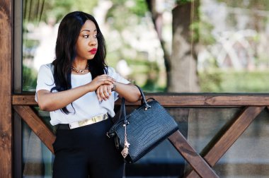 Şık Afro-Amerikan iş kadını çanta sokaklarda şehir ve saatler seyir ile.