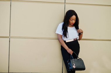 Altın arka plan karşı şehrin sokaklarında üzerinde çanta ile şık Afro-Amerikan iş kadını.