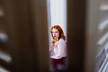 Güzel kırmızı saçlı kız pembe bluz ve yatak odasında şarap el ile kırmızı etek.