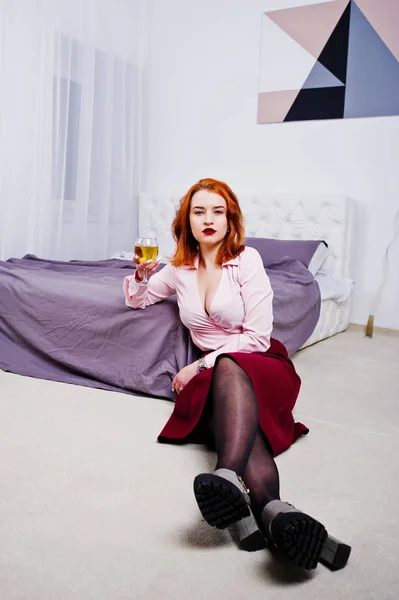 ピンクのブラウスと赤いスカート手で部屋のベッド近くのワインでゴージャスな赤い髪の女の子 — ストック写真