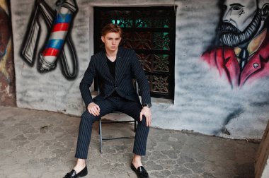 Siyah ceketli genç şık maço çocuk Sokağı'nın açık poz verdi. Grafiti berber duvara oturan inanılmaz modeli adam.