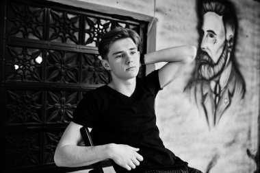 Siyah ceketli genç şık maço çocuk Sokağı'nın açık poz verdi. Grafiti berber duvara oturan inanılmaz modeli adam.