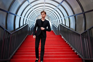 Siyah ceketli genç şık maço çocuk Sokağı'nın açık poz verdi. İnanılmaz modeli adama kırmızı merdiven tonnel.