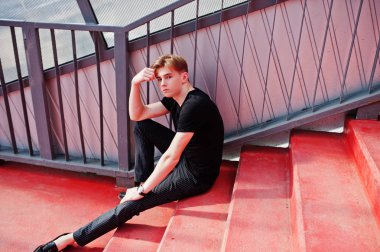 Siyah ceketli genç şık maço çocuk Sokağı'nın açık poz verdi. İnanılmaz modeli adama kırmızı merdiven tonnel.