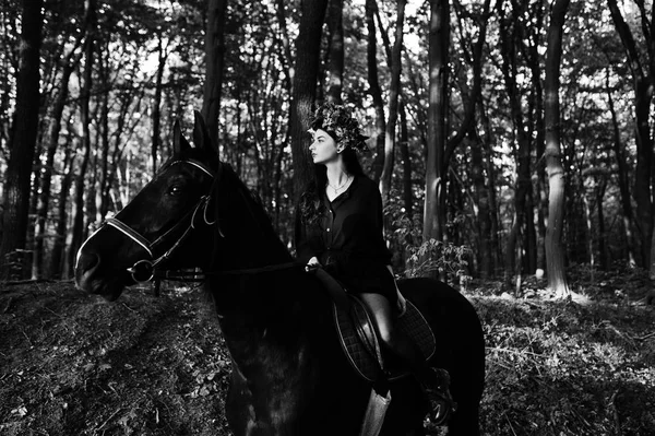 神秘女孩在花圈穿黑色在马在木头 — 图库照片