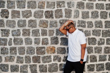 Aslında saç ve güneş gözlükleri şık Arap Müslüman çocuk sokaklarda tuğla duvarın karşısında poz verdi.