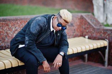 Aslında saç ve güneş gözlükleri şık Arap Müslüman çocuk sokaklarda bankta oturan poz verdi.